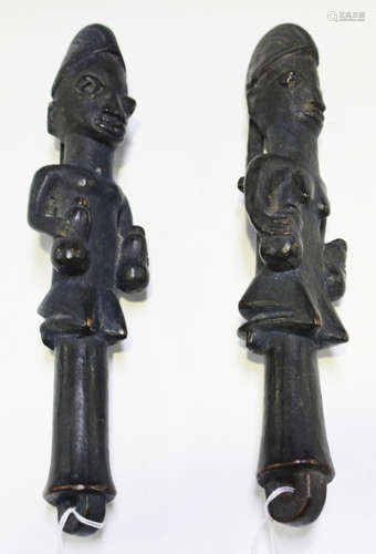 A pair of Yoruba male and female carved wooden eshu dance wands, Nigeria, both with overall black