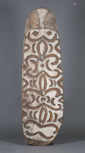 A Papua New Guinea carved wooden shield, early 20th century, the front carved in relief and coloured