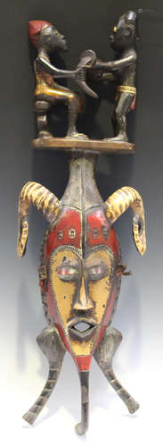 A Senufo carved and painted wooden mask, Ivory Coast, well modelled with a figural surmount and