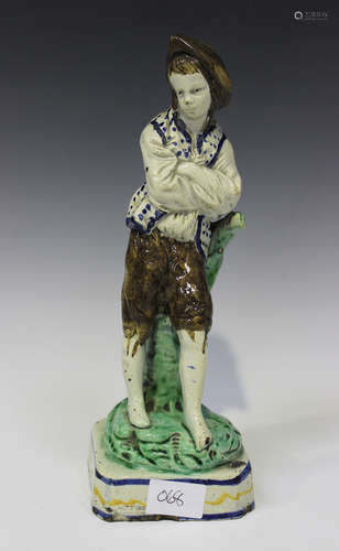 A pearlware figure of Simon, circa 1800, modelled as a boy standing with his arms folded, leaning