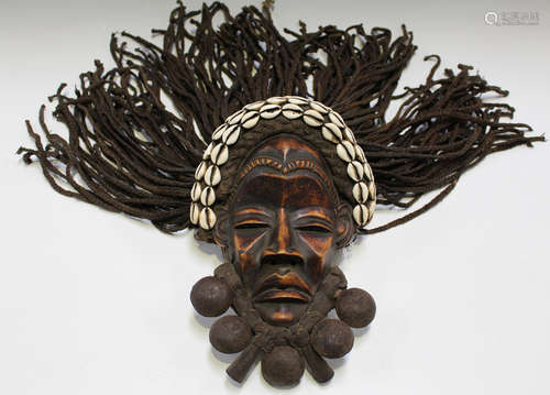 A Dan carved and stained wooden mask, Ivory Coast, with applied cowrie shells and woven string