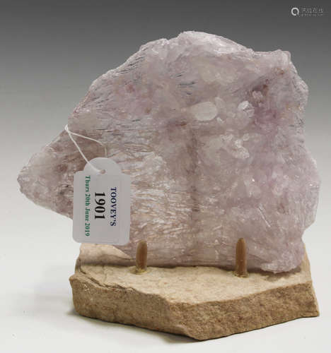 A thin pink-toned quartz specimen of 'angel's wing' form, length 17cm, raised on a display stand.