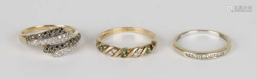 A 9ct gold, diamond and black diamond ring in a twist design, a 9ct gold, diamond and emerald set