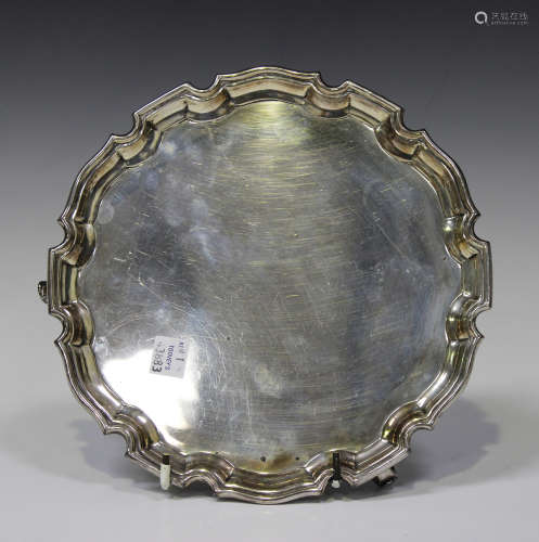An Elizabeth II silver circular salver with shaped piecrust rim, raised on claw and ball feet,