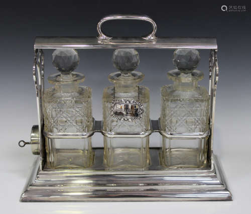 An Edwardian plated 'The Only Holdfast' three-bottle tantalus with pierced sides, on a rectangular