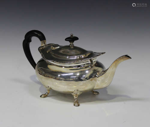 A George V silver three-piece tea set of oval form with wavy rims, on scroll legs, comprising