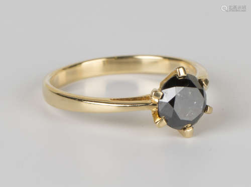 An 18ct gold ring, claw set with a circular cut black diamond, ring size approx N1/2.Buyer’s Premium