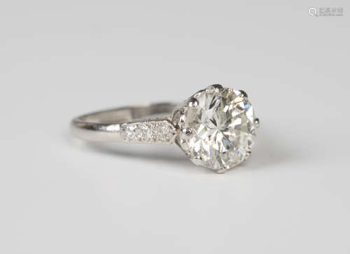 A platinum and diamond ring, claw set with the principal circular cut diamond between diamond set
