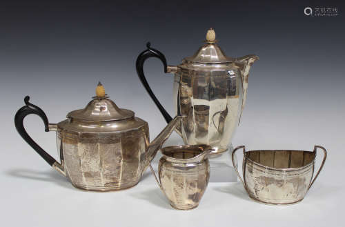 A George V silver three-piece tea set of faceted oval form with a band of bright cut engraved detail