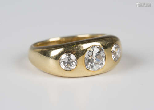 A gold and diamond three stone ring, gypsy set with a row of cushion shaped diamonds with the