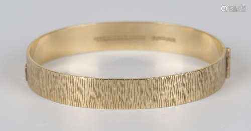 A 9ct gold oval hinged bangle, decorated with a textured finish, Birmingham 1972, inside width 5.