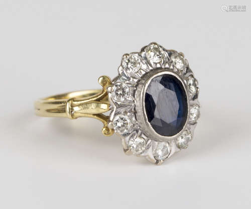 An 18ct gold, sapphire and diamond cluster ring, mounted with an oval cut sapphire within a surround