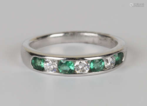 An 18ct white gold, emerald and diamond half-hoop ring, mounted with four circular cut emeralds