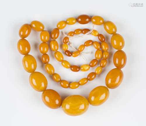 A single row necklace of forty-nine graduated oval vari-coloured opaque butterscotch amber beads,