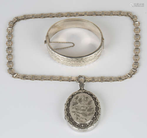 A silver oval hinged bangle, the front with engraved decoration, Birmingham 1950, inside diameter