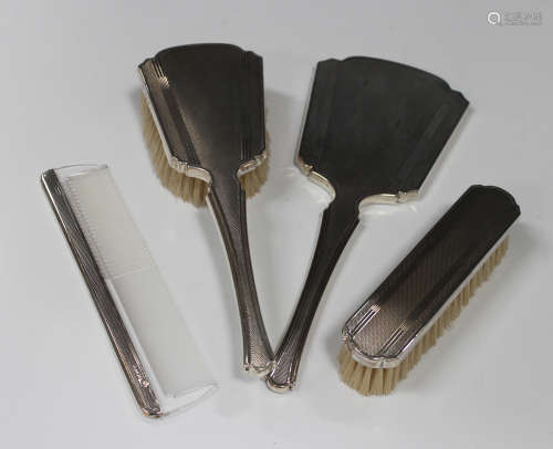 An Elizabeth II silver four-piece dressing table set, comprising hand mirror, hairbrush, clothes