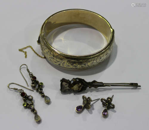 A silver gilt oval hinged bangle with foliate and scroll engraved decoration, on a snap clasp,