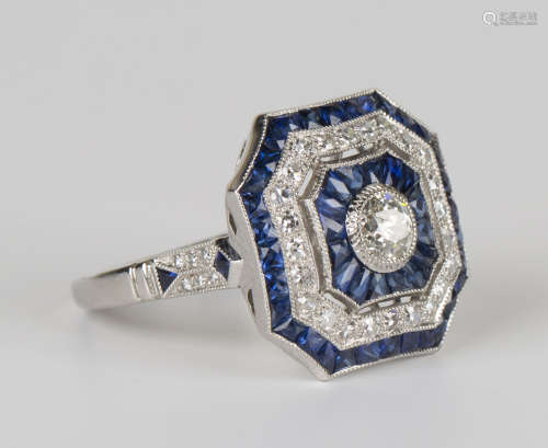 A platinum, diamond and sapphire cluster ring, collet set with the principal circular cut diamond