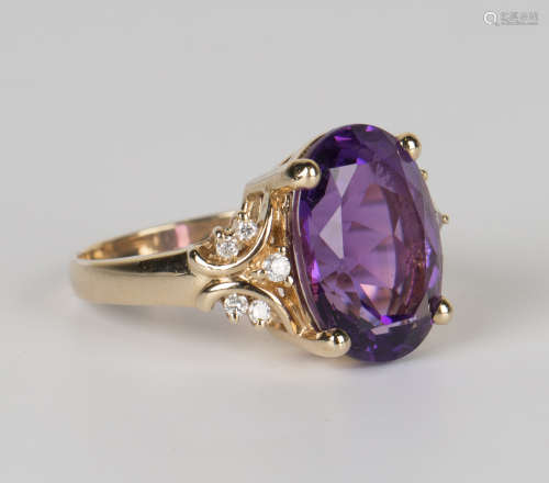 A gold, amethyst and diamond ring, claw set with an oval cut amethyst between diamond set five stone