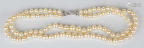 A two row necklace of graduated cultured pearls on a French white gold and diamond set figure of