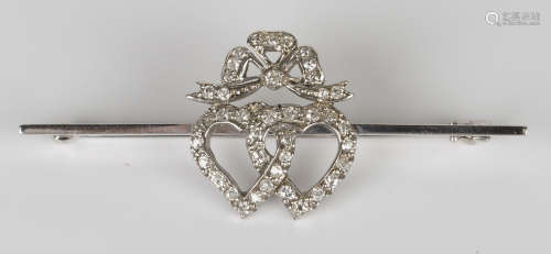 A white gold and diamond bar brooch, the front mounted with a twin entwined heart motif and a ribbon