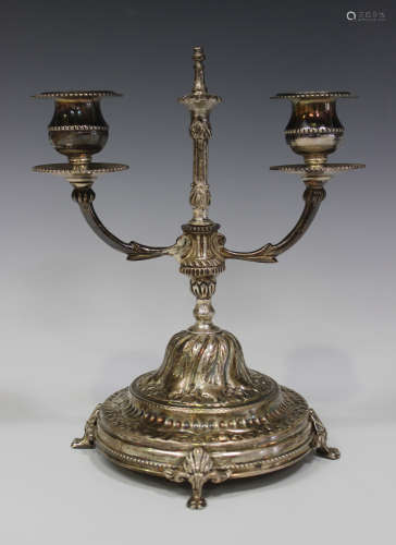 An Egyptian silver twin branch candelabrum, raised on a domed foliate decorated circular base and