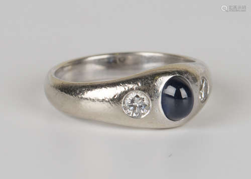 A white gold, sapphire and diamond set three stone ring, gypsy set with an oval cabochon sapphire