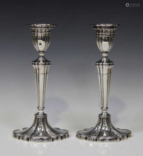 A pair of Elizabeth II silver candlesticks, each with a lobed urn shaped sconce above a tapering