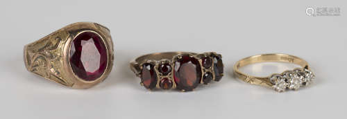 A 9ct gold and diamond three stone ring, a gold and garnet seven stone ring and a gold and oval