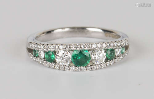 An 18ct white gold, emerald and diamond ring, mounted with a row of five graduated circular cut