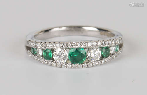 An 18ct white gold, emerald and diamond ring, mounted with a row of five graduated circular cut