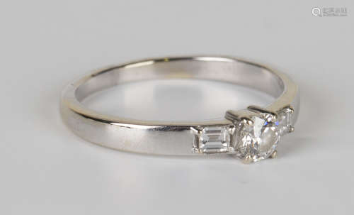 An 18ct white gold and diamond ring, claw set with the principal circular cut diamond between