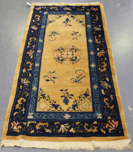 A Chinese rug, mid/late 20th century, the apricot field sparsely decorated with floral sprays,