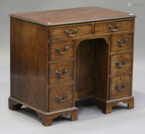 A George III mahogany kneehole desk, fitted with an arrangement of eight drawers and a cupboard,
