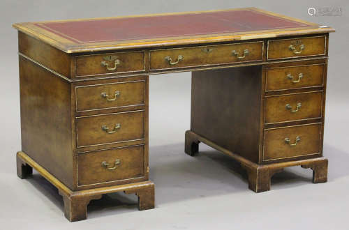 A 20th century reproduction walnut twin pedestal desk, the top inset with a gilt-tooled red