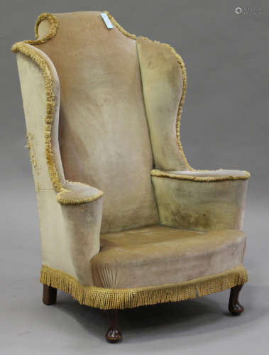 An early 20th century Queen Anne style wingback armchair, upholstered in velour, on carved