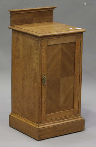 An early 20th century oak bedside cabinet, probably by Heals, the moulded top above a cupboard, on a
