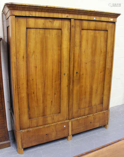 A mid-19th Century German satin birch armoire, the stepped pediment above two panel doors and two