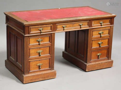 A late Victorian walnut twin pedestal desk, the moulded top above an arrangement of nine drawers,