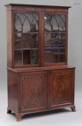 A George IV figured mahogany bookcase cabinet, the moulded pediment above a pair of astragal