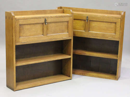 A near pair of early 20th century Arts and Crafts oak bookcase cabinets, each fitted with a fall