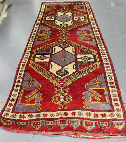 A Turkish runner, 20th century, the claret field with a pair of bold polychrome medallions, within