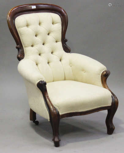 A Victorian mahogany showframe armchair with carved decoration, upholstered in buttoned cream