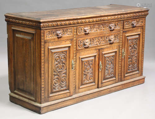 A late Victorian oak sideboard with carved decoration, fitted with four drawers and cupboards, on