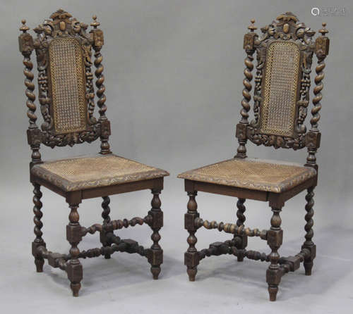 A pair of Victorian Jacobean Revival carved oak side chairs with cane seats and back, raised on