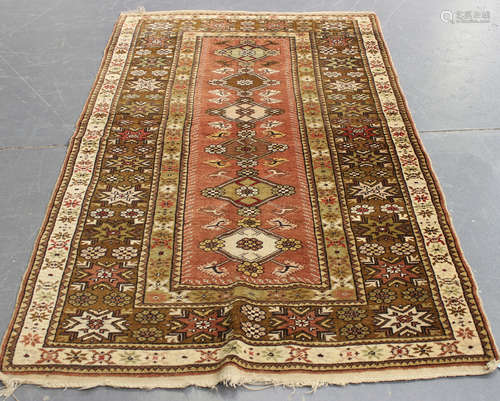 A Milas rug, Turkey, mid-20th century, the pink field with a column of lozenge medallions, within