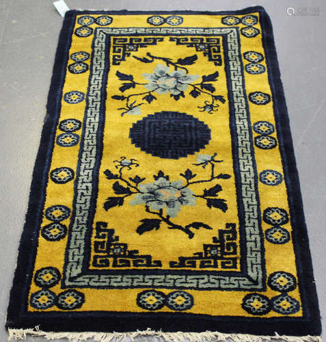 A small Chinese rug, late 20th century, the yellow field with a dark blue medallion and flowerheads,