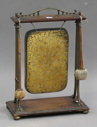 An Edwardian oak and brass mounted gong stand, fitted with a rectangular gong supported by cast claw