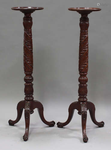 A pair of 20th century reproduction mahogany torchères, the carved stems raised on tripod cabriole