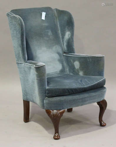 An early 20th century Queen Anne Style wingback armchair, upholstered in blue velour, raised on